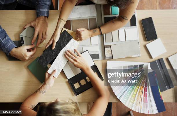High angle view of a young female interior designer discussing tiles with a young couple during a meeting in her office